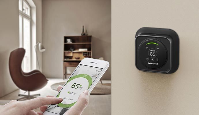 Expert adjusting temperature using a mobile app while the thermostat displays the current temperature