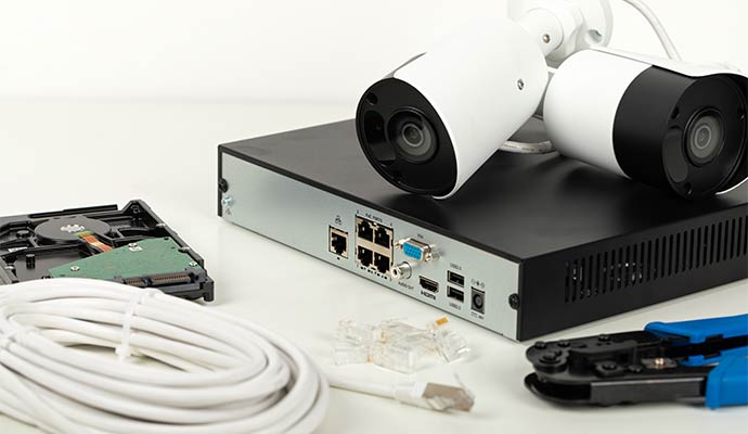 A network video recorder system with security cameras, hard drive, ethernet cables, and installation tools on a white surface