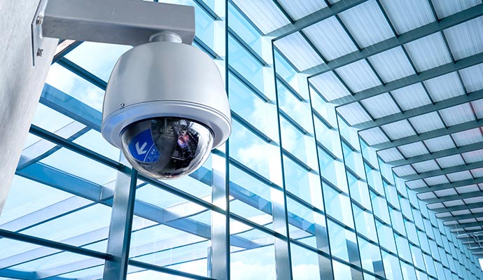 Surveillance camera mounted on an interior wall of modern glass building